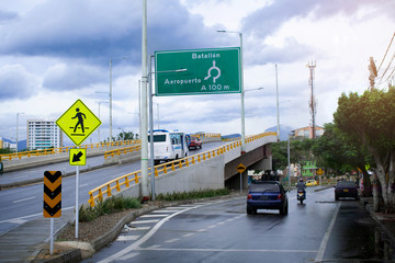 aviso de señal de transito en un puente de una ciudad con autos alrededor