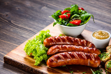 Grilled sausages and vegetables on cutting board