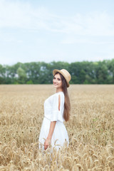 Naklejka na ściany i meble Beauty girl portrait in wheat field at sunset. Attractive young woman smiling and enjoying life. Beautiful brunette with a healthy long haircut. Wellness concept. The concept of a rich harvest.