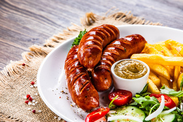 Grilled sausages, French fries and vegetables
