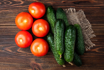 Fresh cucumbers and tomatoes on dark wooden background
