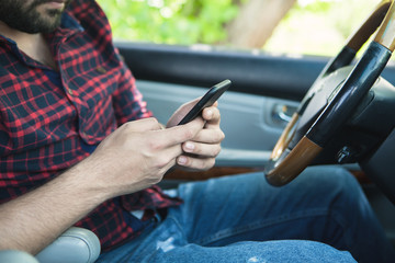 young man sitting driving a car using a mobile phone