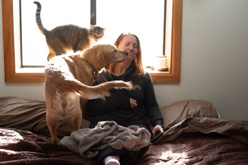Woman getting loved by cat and dog kisses