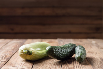Trendy ugly organic squash and cucumber on natural wooden table on dark blurred background. Copy space.