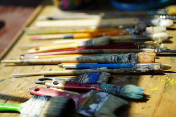 Fototapeta premium Artist brushes lie on a wooden board. The working environment of the artist for the background.