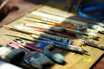 Obraz premium Artist brushes lie on a wooden board. The working environment of the artist for the background.