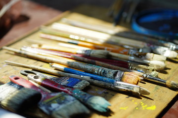 Obraz premium Artist brushes lie on a wooden board. The working environment of the artist for the background.