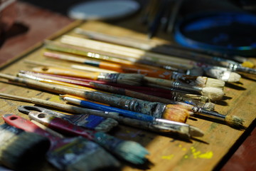 Obraz premium Artist brushes lie on a wooden board. The working environment of the artist for the background.