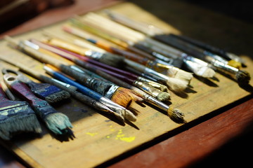 Fototapeta premium Artist brushes lie on a wooden board. The working environment of the artist for the background.