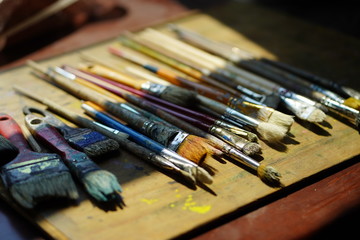 Fototapeta premium Artist brushes lie on a wooden board. The working environment of the artist for the background.