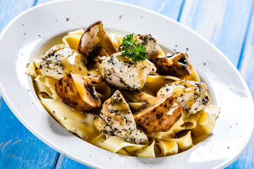 Pasta with chicken and champignon on wooden background