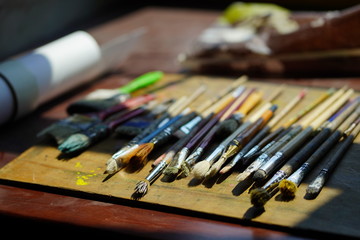 Naklejka premium Artist brushes lie on a wooden board. The working environment of the artist for the background.