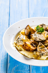 Pasta with chicken and champignon on wooden background