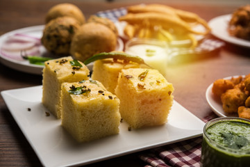 Indian Tea time snacks  in group includes Veg Samosa, Kachori/kachaudi, aloo bonda, khaman dhokla, bread, onion,chilli and moong pakora/pakoda/bhaji/bhajji/Bhajiya/bajji with sauces, selective focus