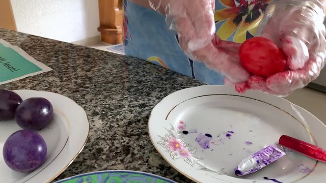 A woman in gloves paints eggs