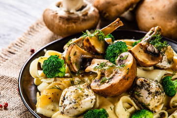 Pasta with chicken and champignon on wooden background