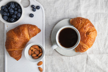 Cup of black coffee with croissant on  table. The concept of breakfast, flat lay, top view.