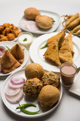 Indian Tea time snacks  in group includes Veg Samosa, Kachori/kachaudi, aloo bonda, khaman dhokla, bread, onion,chilli and moong pakora/pakoda/bhaji/bhajji/Bhajiya/bajji with sauces, selective focus