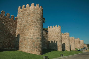 Stone towers on the large city wall next to street at Avila