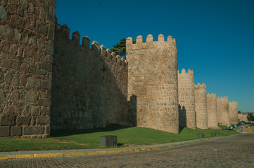 Fototapeta na wymiar Stone towers on the large city wall next to street at Avila