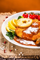 Fried pork chop with vegetables and mushrooms on wooden background