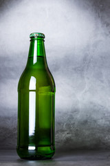Green glass bottle close-up on a dark gray background. There is a place for text, inscriptions.