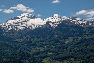 Panorama of an alpine landscape with high mountains, green meadows and trees in spring with snow in Swiss Alps-Switzerland