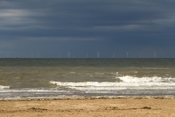 Offshore windfarm on the horizon seen from a beach cloudy sky