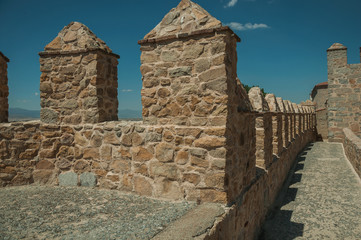 Pathway over thick stone wall with battlement around Avila