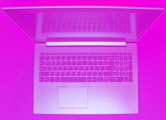 Modern laptop with vibrant pink toned. Minimalism. Top view