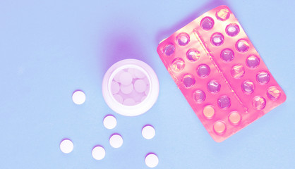 Minimalism medical concept. Blisters and a bottle of pills on a blue background.