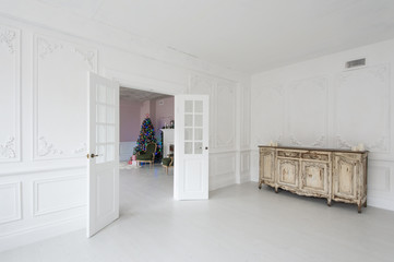Luxurious bright interior with stucco walls, vintage chest of drawers and Christmas tree.