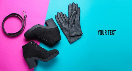 Minimalism collage of fashionable women's shoes and accessories on pink blue background. Black boots, leather gloves, belt. Copy space. Top view