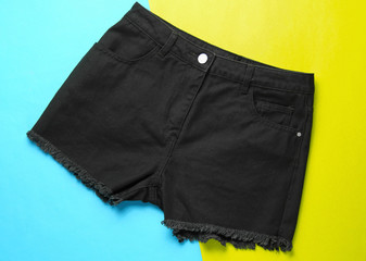 Fashionable black denim shorts on paper background. Top view. Minimalism fashion concept