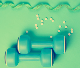 Sport weight loss concept. Dumbbells, ruler, pills on a blue background. Minimalism. Top view