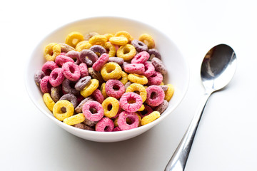 Multicolored round-shaped flakes lie in a bowl on a light background. Delicious and healthy breakfast for children.