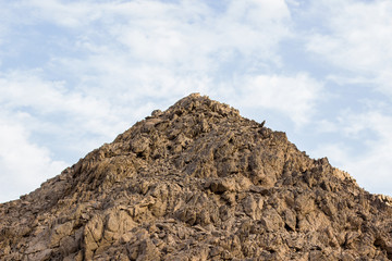 symmetric cone shape of stone sharp mountain top point on blue sky with white clouds background 