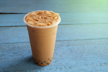 Pearl Bubble milk tea with ice in plastic cup on wooden floors