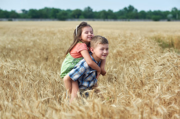 Children on a walk in a field of wheat . Funny brother and sister in the countryside