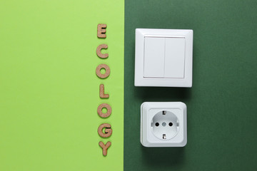 Power socket and switch with the word ecology on green background. Top view