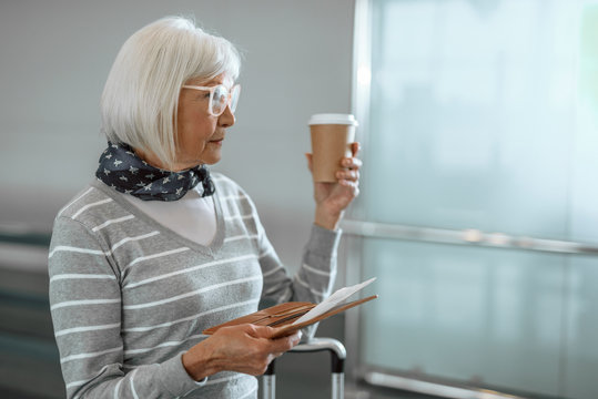 Confident mature female standing with coffee at airport
