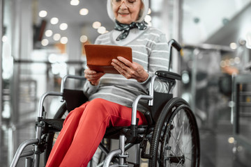 Old woman on disabled carriage with ticket at airport