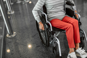 Obraz premium Mature lady on disabled carriage moving at hall