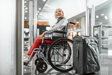 Smiling old lady on disabled carriage waiting at hall
