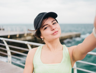Young athletic woman in sportswear taking selfie on the beach. Sports lifestyle