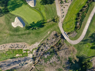Aerial top view of a green golf course during sunny day. South California.