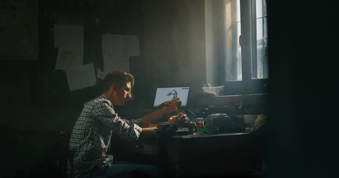 Slow motion of an young professional engineer is working on projection of an innovative technology mechanical arm in his workshop.