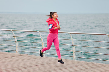 Fototapeta na wymiar Fit woman in sportswear is running on the beach. Morning running. Healthy lifestyle concept.