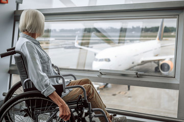 Cheerful mature lady on disabled carriage in airport