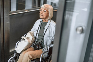 Smiling old female on disabled carriage using lift